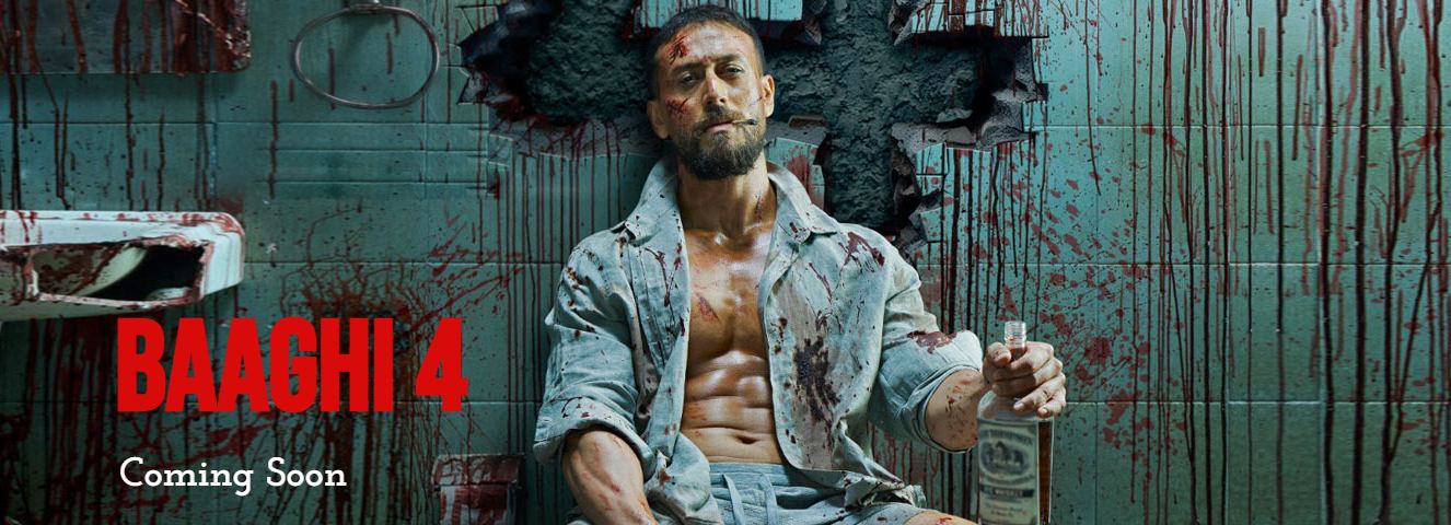 Tiger Shroff, bloodied and intense, sits in a shattered prison cell holding a bottle.