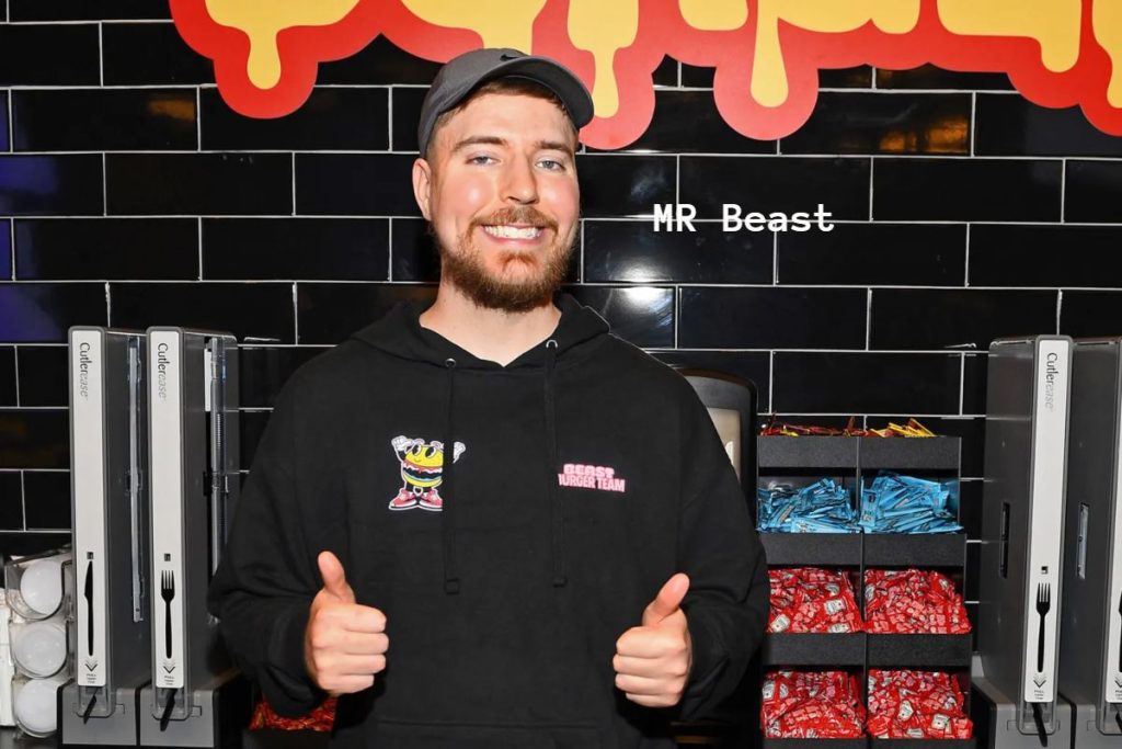 Man with dollar bills sticking out of his ears wearing a "MrBeast" hoodie.